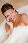 Surprised looking woman with her cellphone in the tub