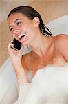 Laughing woman with her cellphone in the tub