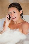 Surprised looking woman with her mobile phone in the tub