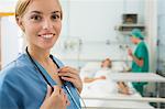 Blonde nurse smiling while touching a stethoscope