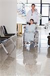 Smiling doctor wheeling a smiling girl in a wheelchair