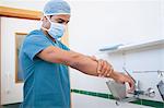 Surgeon with a surgical mask washing his hand