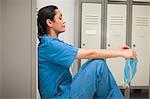 Thinking female surgeon sitting in a locker room