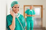 Smiling surgeon standing in a hallway while holding a phone