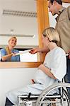 Smiling nurse giving a paper to a man and a woman in a wheelchair