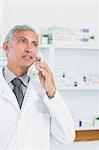 Pharmacist standing in a pharmacy while telephoning