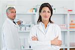 Female pharmacists with her arms folded and a colleague