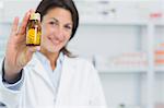 Female pharmacist showing pills and standing in a pharmacy