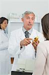 Pharmacist holding a flask of pills in front of a customer