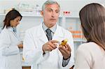 Pharmacist talking to a customer while holding a flask of pills