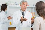 Hospital pharmacist talking to a customer while holding a flask of pills