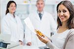 Client holding a paper and pills while standing in a pharmacy