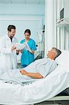 Patient lying on a bed while looking at a doctor and a nurse