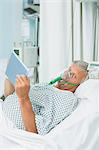 Senior male patient wearing an oxygen mask while holding a tactile tablet in his hands