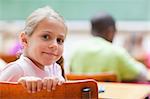 Smiling little girl sitting at school desk