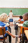 Back view of boy giving letter to schoolfellow