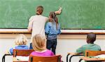 Back view of teacher and pupil wiping the blackboard