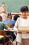 Smiling student standing with pile of books