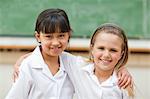 Happy girls in school uniform in front of blackboard