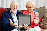 Senior couple holding up a blank tablet PC, ready for your text or picture.