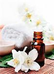 Essential oil with jasmine flower on wooden background