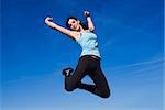 Attractive happy young woman jumping - sky background