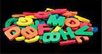 A pile of colorful foam letters isolated on black.