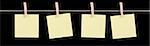 Four blank yellow sticky notes held on a string by pegs isolated on a black background.