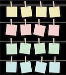 Four sets of blank sticky notes held on strings by clips isolated on a black background.