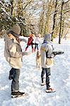Family Having Snowball Fight In Snowy Woodland