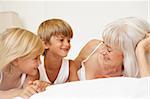 Grandmother Relaxing On Bed With Grandchildren