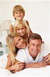 Portrait Of Young Family Relaxing In Bed Together