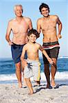 Grandfather, Father and Grandson Running Along Beach