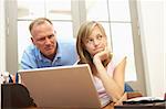 Angry Father And Teenage Daughter Using Laptop At Home