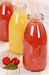 Freshly squeezed juice from red fruits and oranges in bottles