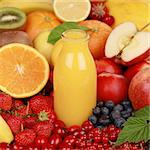 A bottle of orange smoothie surrounded by fresh fruits