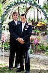 Newly married gay couple posing for a portrait under the wedding arch.