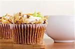 Decorated carrot cupcake next to a white cup.