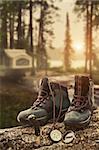 Hiking boots with compass on tree trunk at campsite