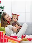 Smiling young mother spending Christmas with baby and pointing on copy space