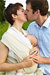 Couple kissing with infant outdoors