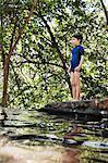 Boy standing by river in forest