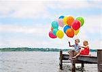 Children holding balloons on wooden pier