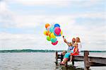 Family holding balloons on wooden pier