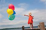 Girl holding balloons on wooden pier