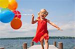 Girl holding balloons on wooden pier