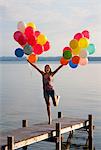 Teenage girl holding balloons on pier