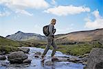 Hiker crossing rocky rural stream