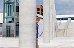 Boy peering out from behind column