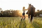 Femme saddling à cheval dans le champ